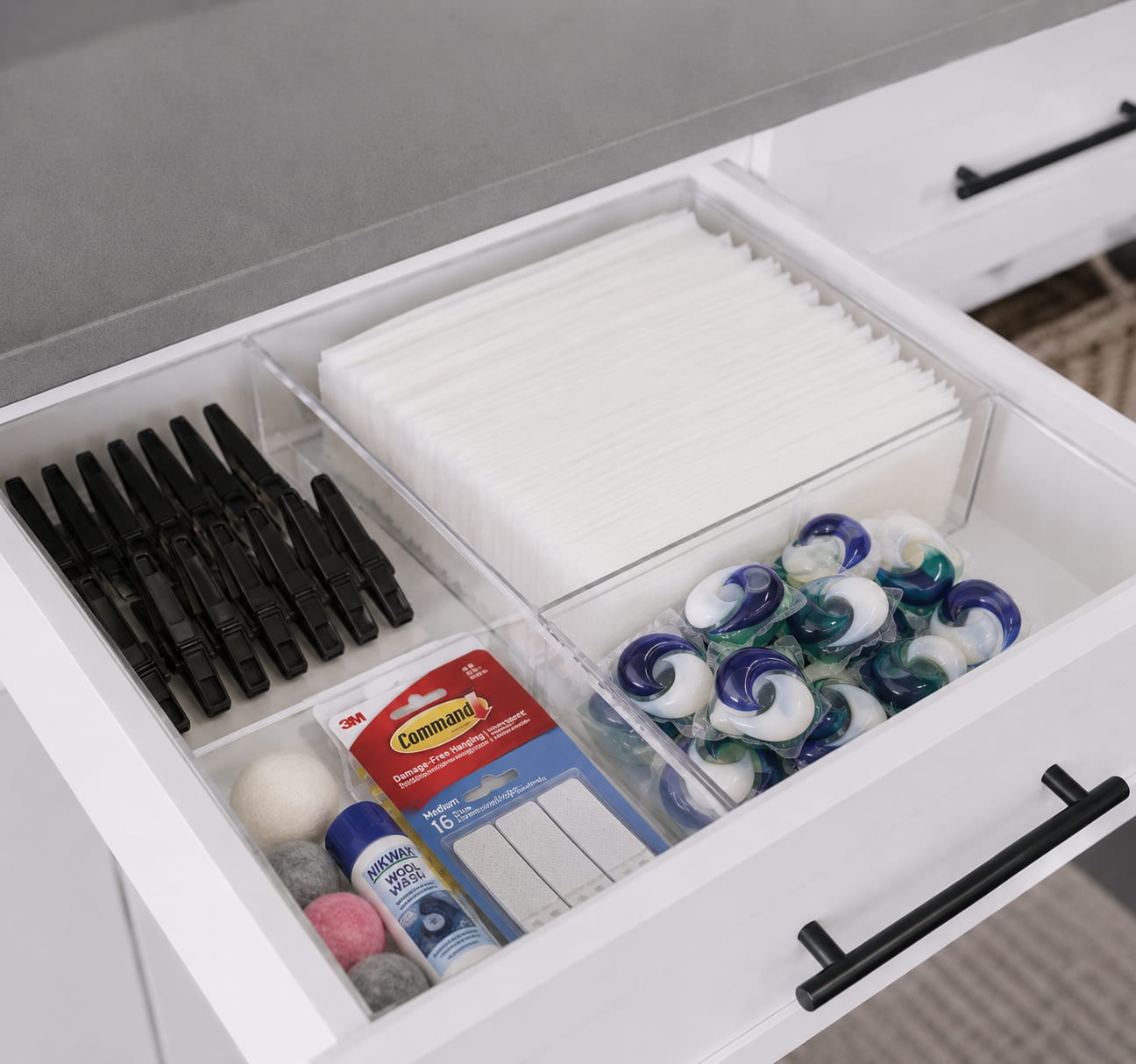 Organized laundry room drawer with labeled dividers for dryer sheets, detergent pods, and wool dryer balls